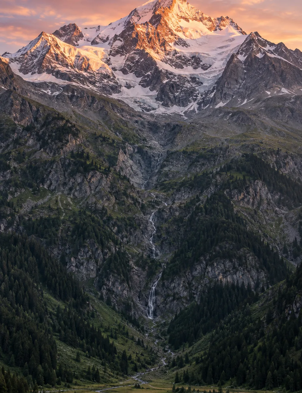 Alpiner Hang vom grünen Tal bis zum schneebedeckten Gipfel im Alpenglühen
